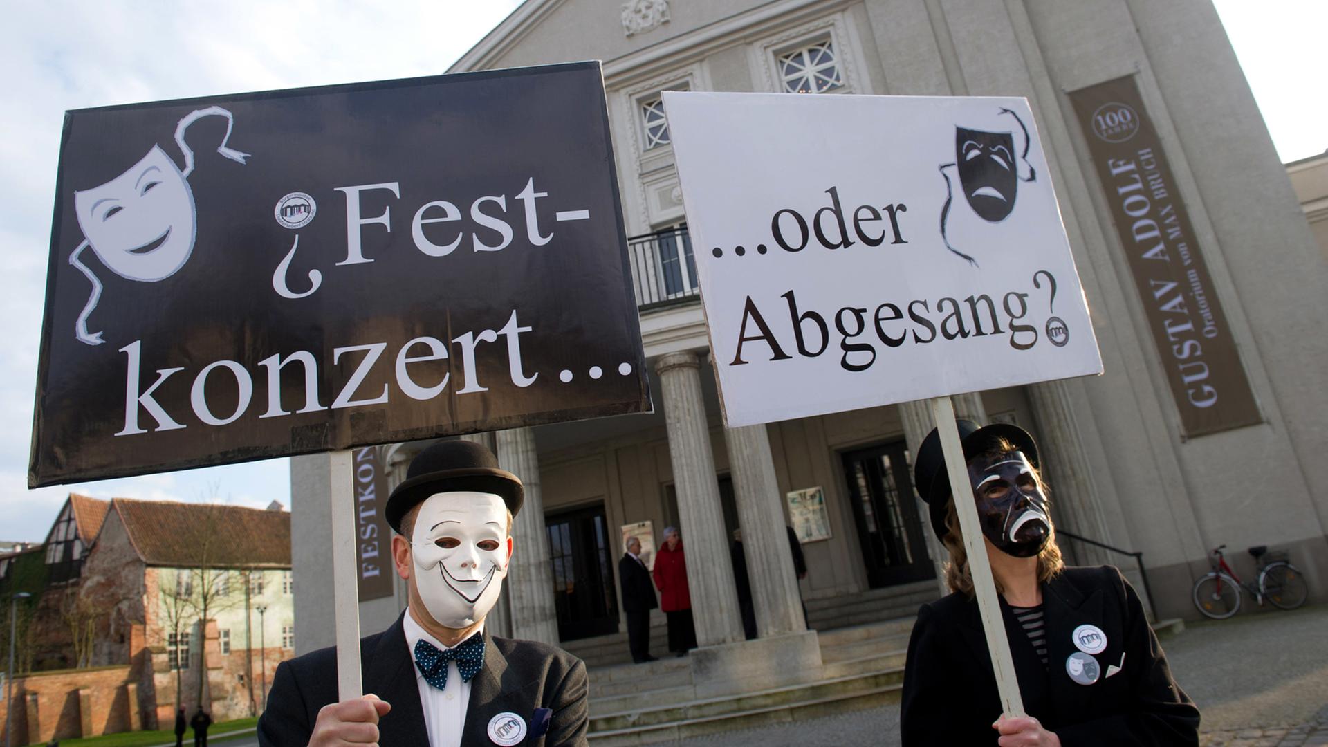 «Festkonzert oder Abgesang?» steht am 08.04.2015 während einer Demonstration vor dem Theater in Stralsund (Mecklenburg-Vorpommern) für den Erhalt der Theater in Vorpommern auf zwei Transparenten. Das Theater Stralsund feierte am 16. September 1916 seine erste Premiere. Foto:Stefan Sauer/dpa «Festkonzert oder Abgesang?» steht am 08.04.2015 während einer Demonstration vor dem Theater in Stralsund (Mecklenburg-Vorpommern) für den Erhalt der Theater in Vorpommern auf zwei Transparenten. Das Theater Stralsund feierte am 16. September 1916 seine erste Premiere. Foto:Stefan Sauer/dpa