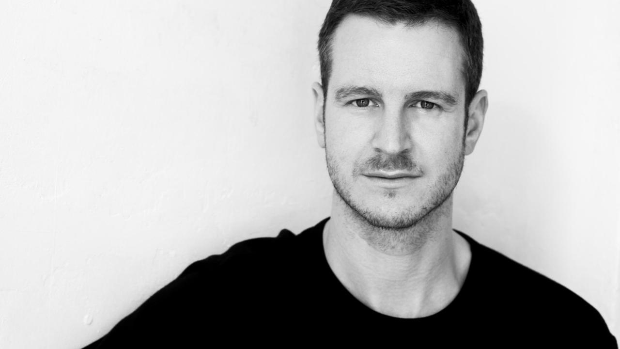 Nils Binnberg steht vor einer weißen Wand und schaut freundlich in die Kamera. Nils Binnberg steht vor einer weißen Wand und schaut freundlich in die Kamera.