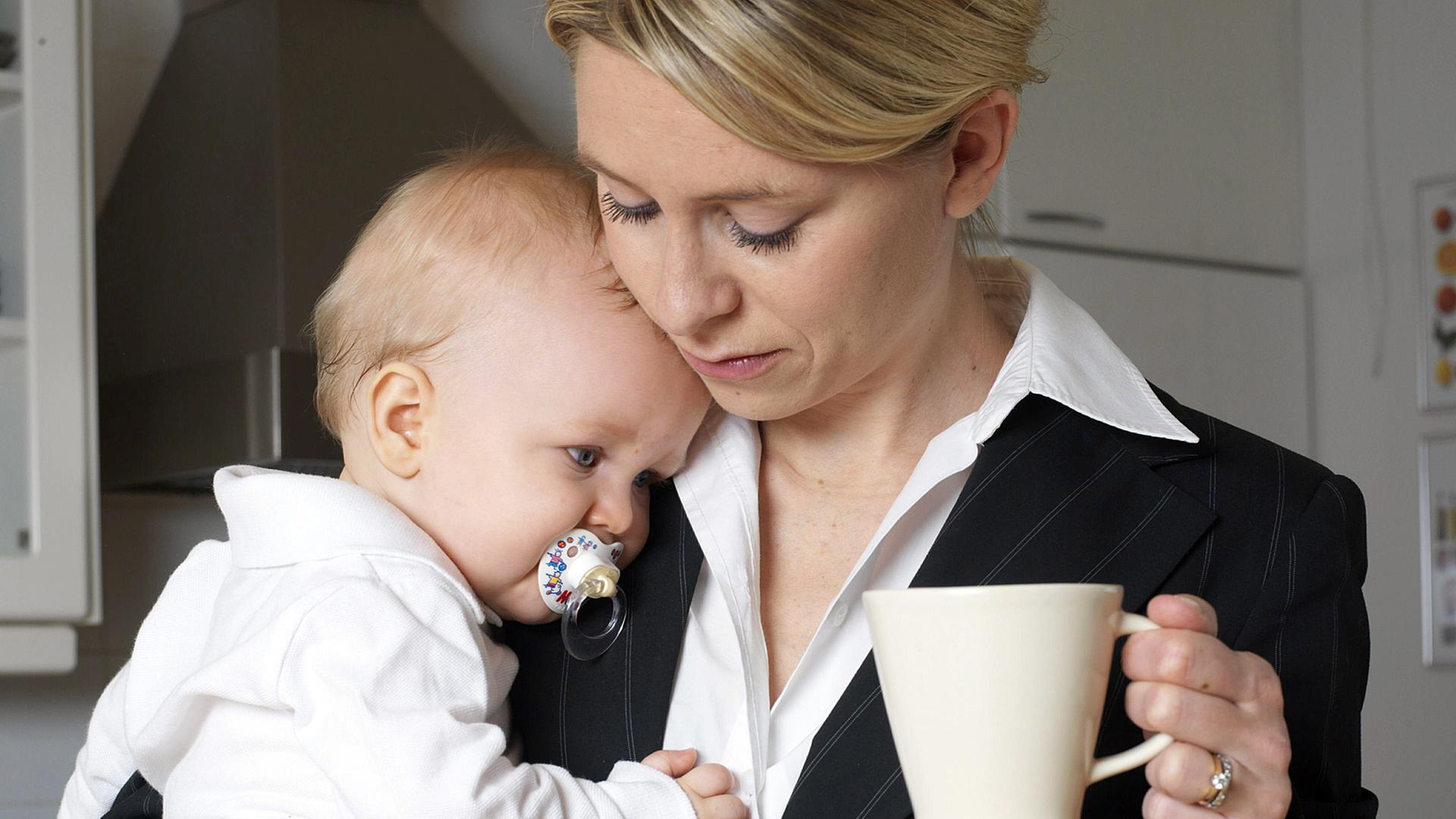 Eine Mutter im Business-Anzug mit ihrem Baby auf dem Arm, in der Hand eine Kaffeetasse. Eine Mutter im Business-Anzug mit ihrem Baby auf dem Arm, in der Hand eine Kaffeetasse.