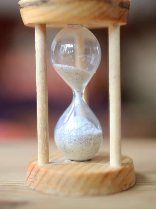 Eine Sanduhr. Das obere Glas ist noch halb voll.