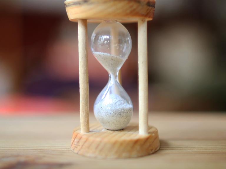 Eine Sanduhr. Das obere Glas ist noch halb voll.