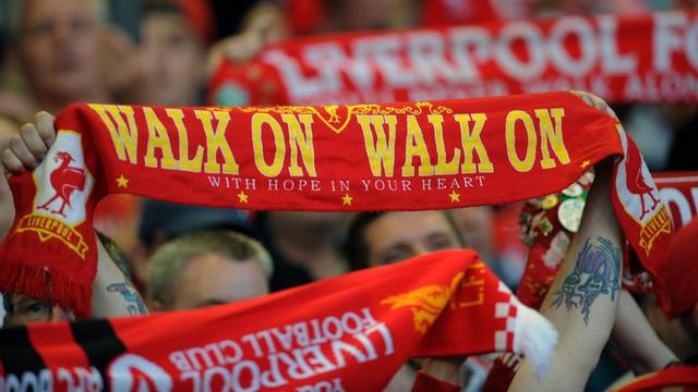 Fans des FC Liverpool halten Schals in die Höhe, auf denen "Walk on" steht.
