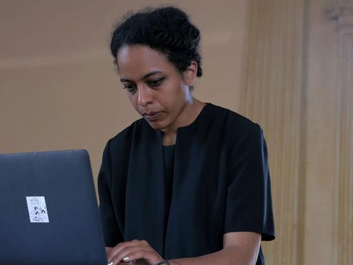 Die Klangkünstlerin Jessica Ekomane steht vor einem Laptop