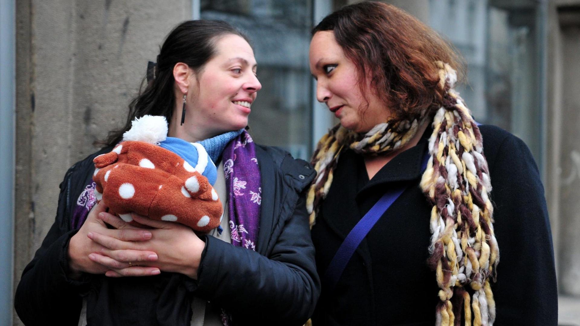 Ein lesbisches Paar mit einem Baby schaut sich an auf dem Weg zu einem Wahllokal im slowenischen Ljubljana. Ein lesbisches Paar mit einem Baby schaut sich an auf dem Weg zu einem Wahllokal im slowenischen Ljubljana.