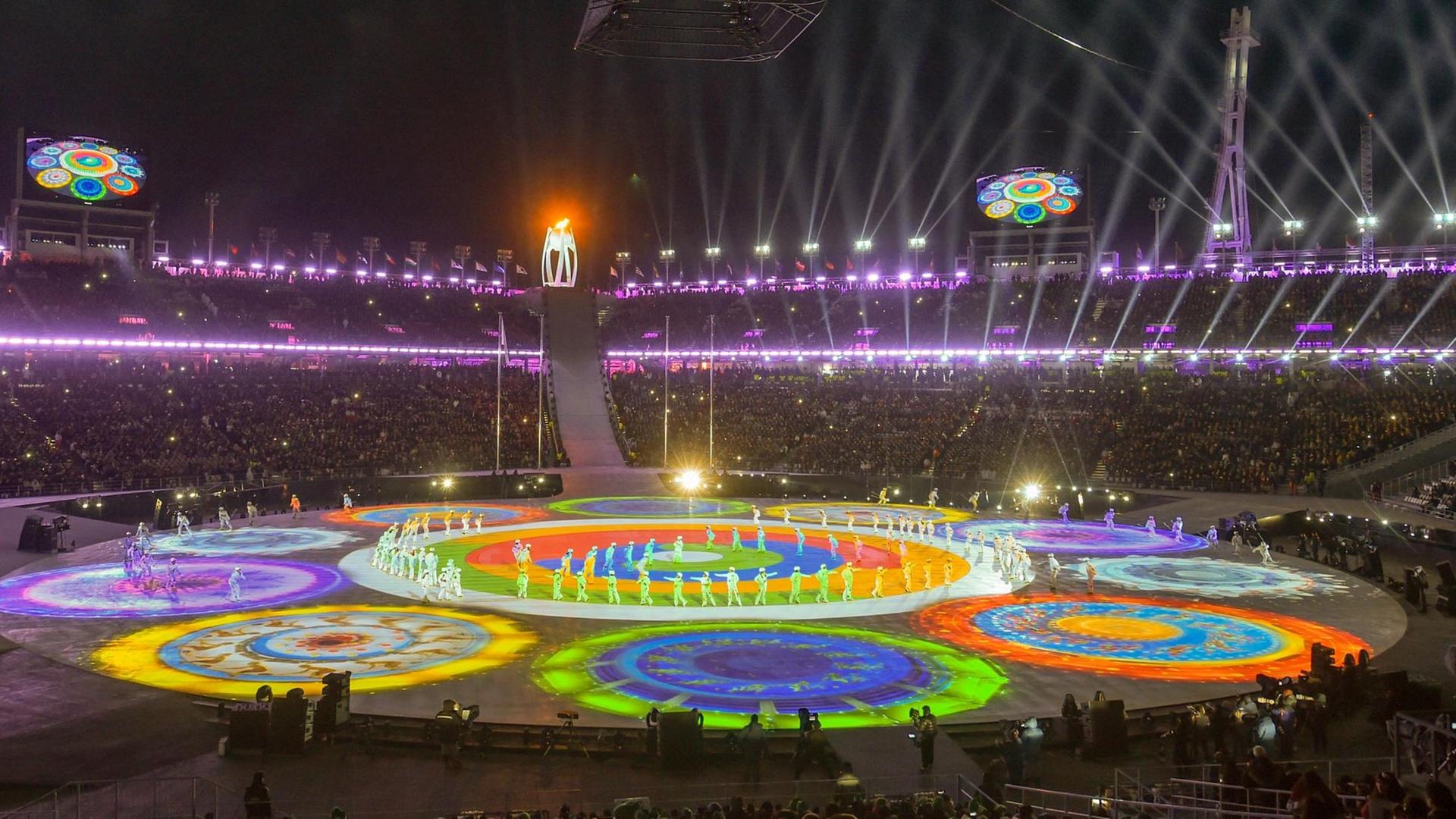 Bei der Schlussfeier im Olympiastadion von Pyeongchang präsentieren Tänzer und Künstler das Showprogramm. Zu sehen sind bunte, kreisförmige Lichtprojektionen.