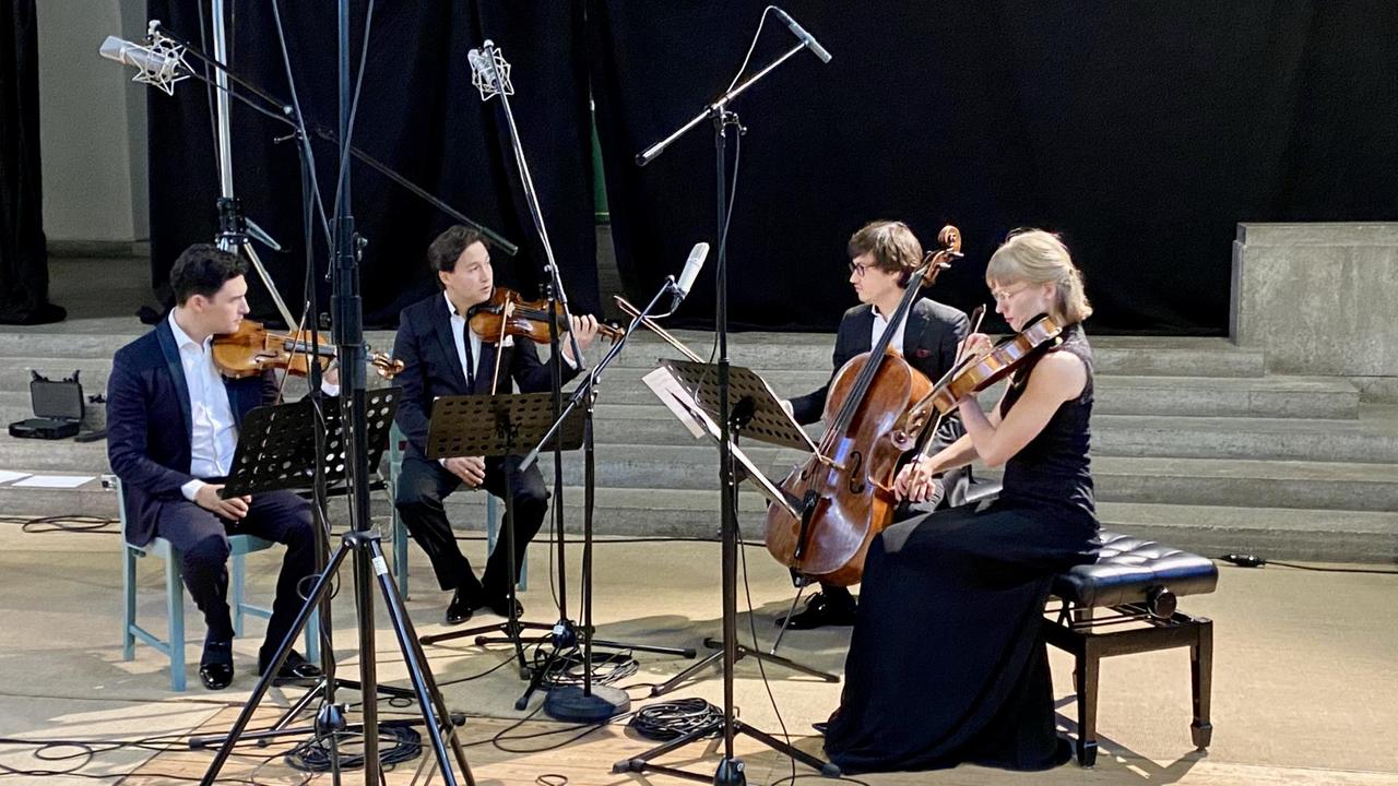 Drei Musiker und eine Musikerin spielen Streichquartett. Drei Musiker und eine Musikerin spielen Streichquartett.