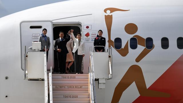 Ehemalige japanische Goldmedaillengewinner nehmen an einem Flugzeug die Olympische Flamme in Empfang.