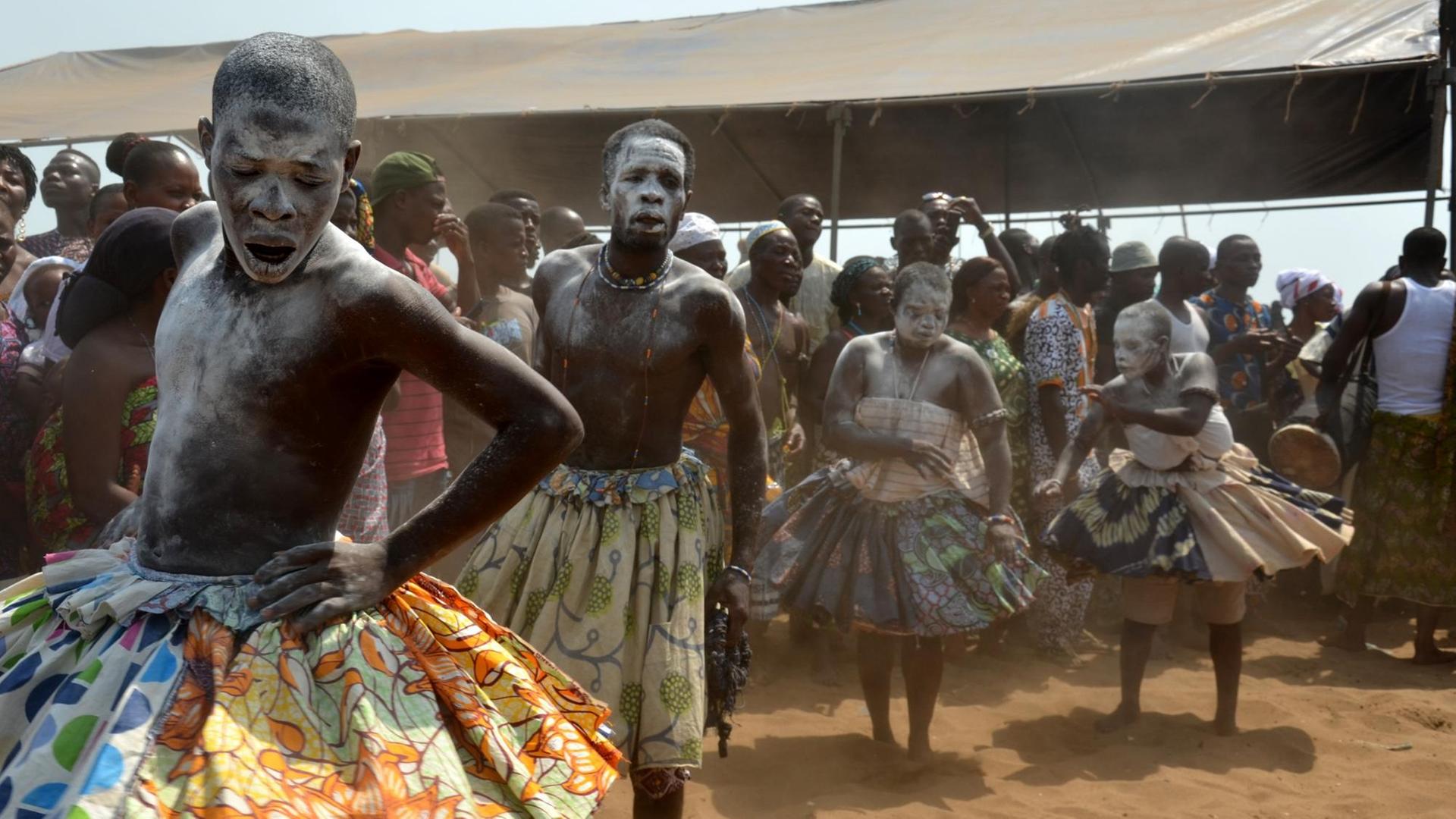 Frauen und Männer in traditioneller Kleidung tanzen am Strand von Ouidah an der Küste Benins am 10. Januar, dem offiziellen Voodoo-Tag. Frauen und Männer in traditioneller Kleidung tanzen am Strand von Ouidah an der Küste Benins am 10. Januar, dem offiziellen Voodoo-Tag.