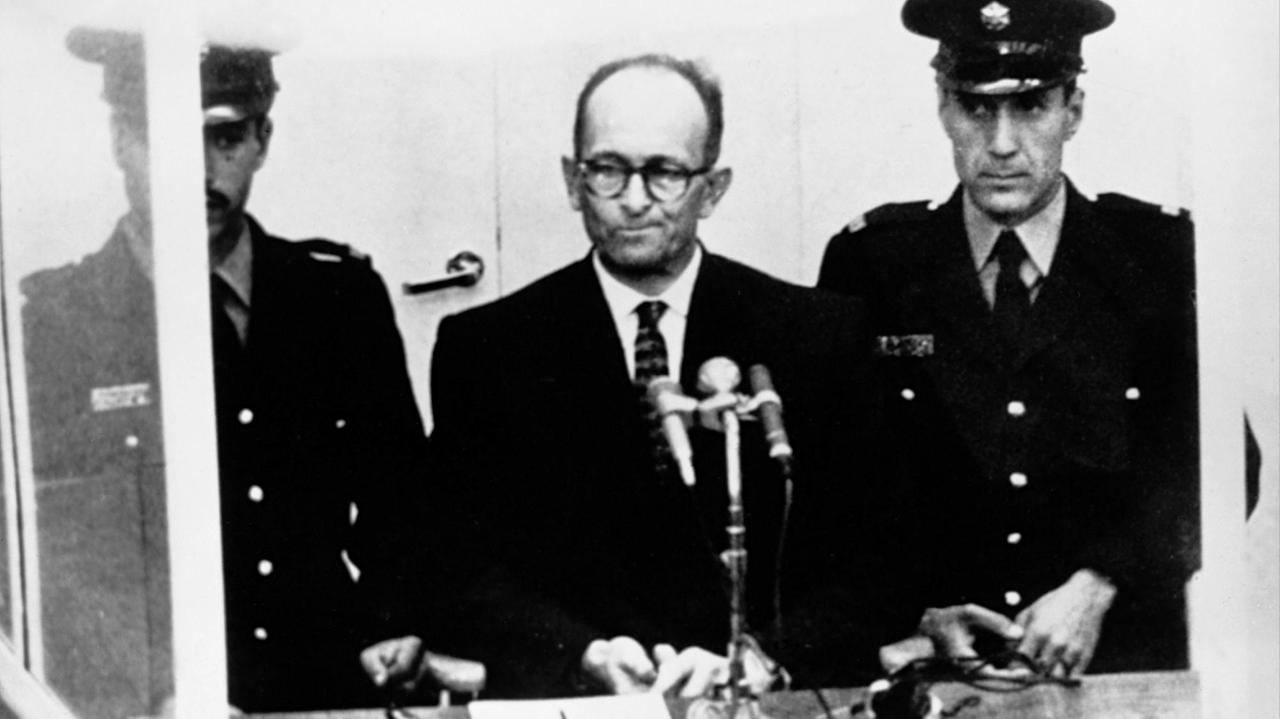 Adolf Eichmann mit zwei Polizisten beim Prozess gegen ihn