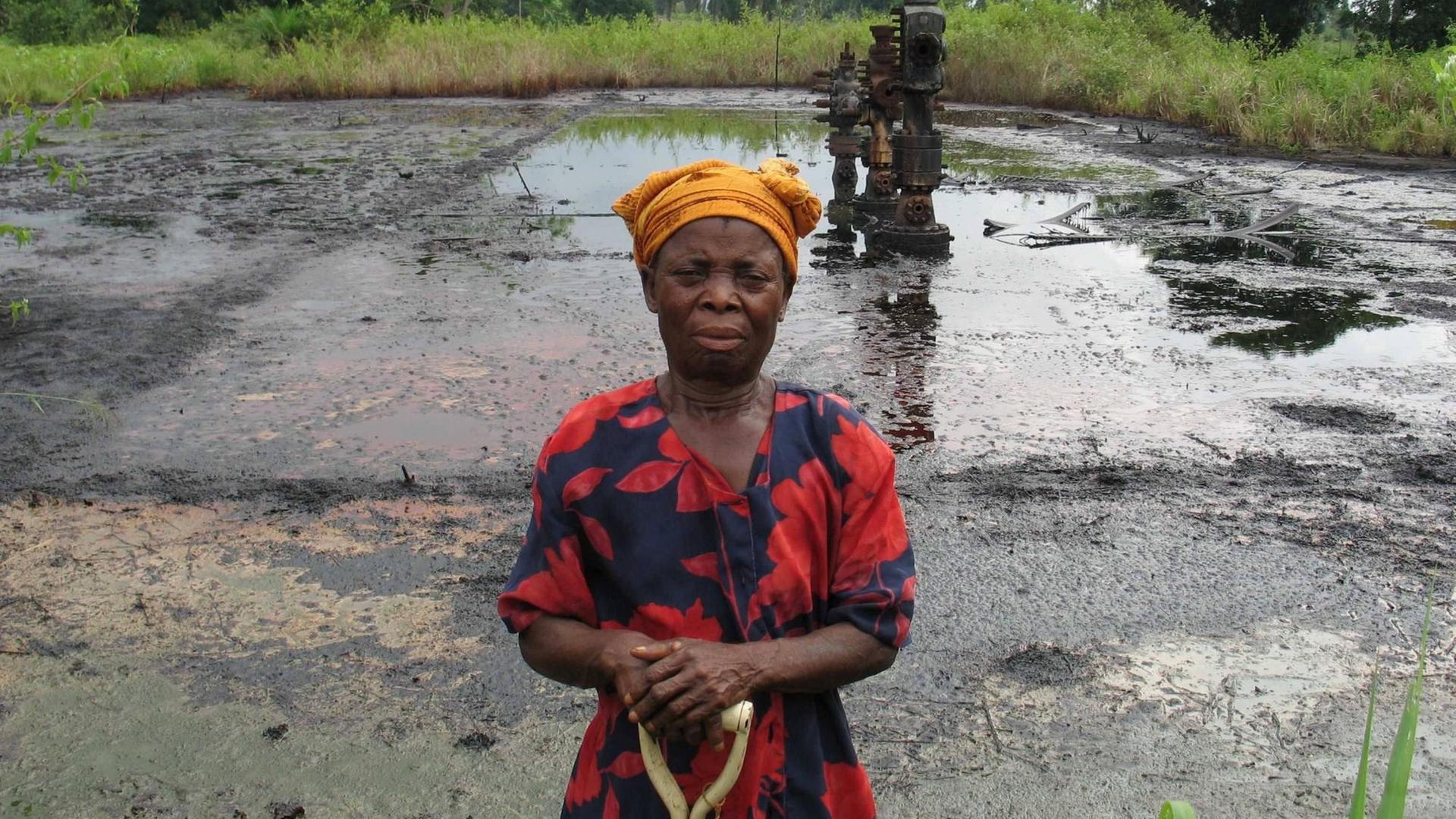 Eine Bäuerin steht vor ihrem Feld, auf dem Öl ist. 