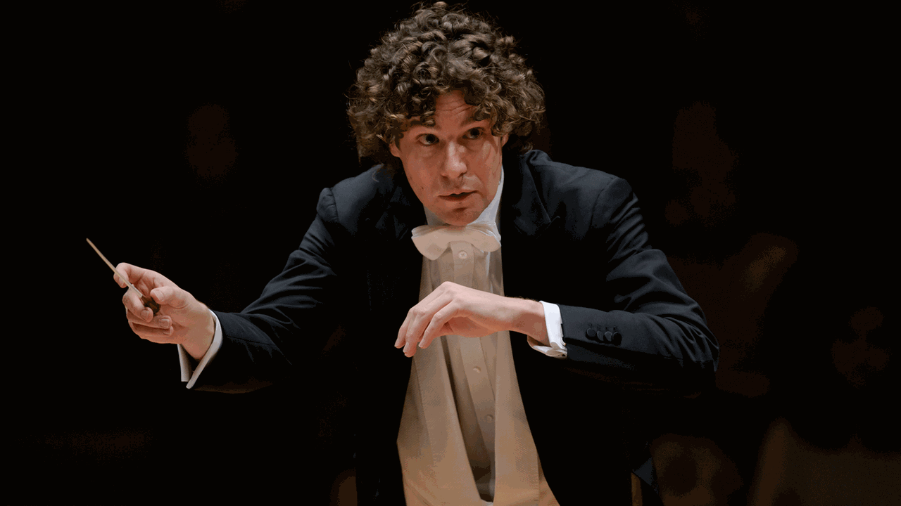 Der Dirigent bei einem konzentrierten Wink zu Musikern im Orchester. Der Dirigent bei einem konzentrierten Wink zu Musikern im Orchester.