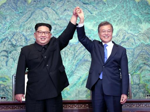 Kim Jong-un un Moon Jae-in halten sich bei ihrem Treffen in Panmunjom an den Händen und diese in die Luft