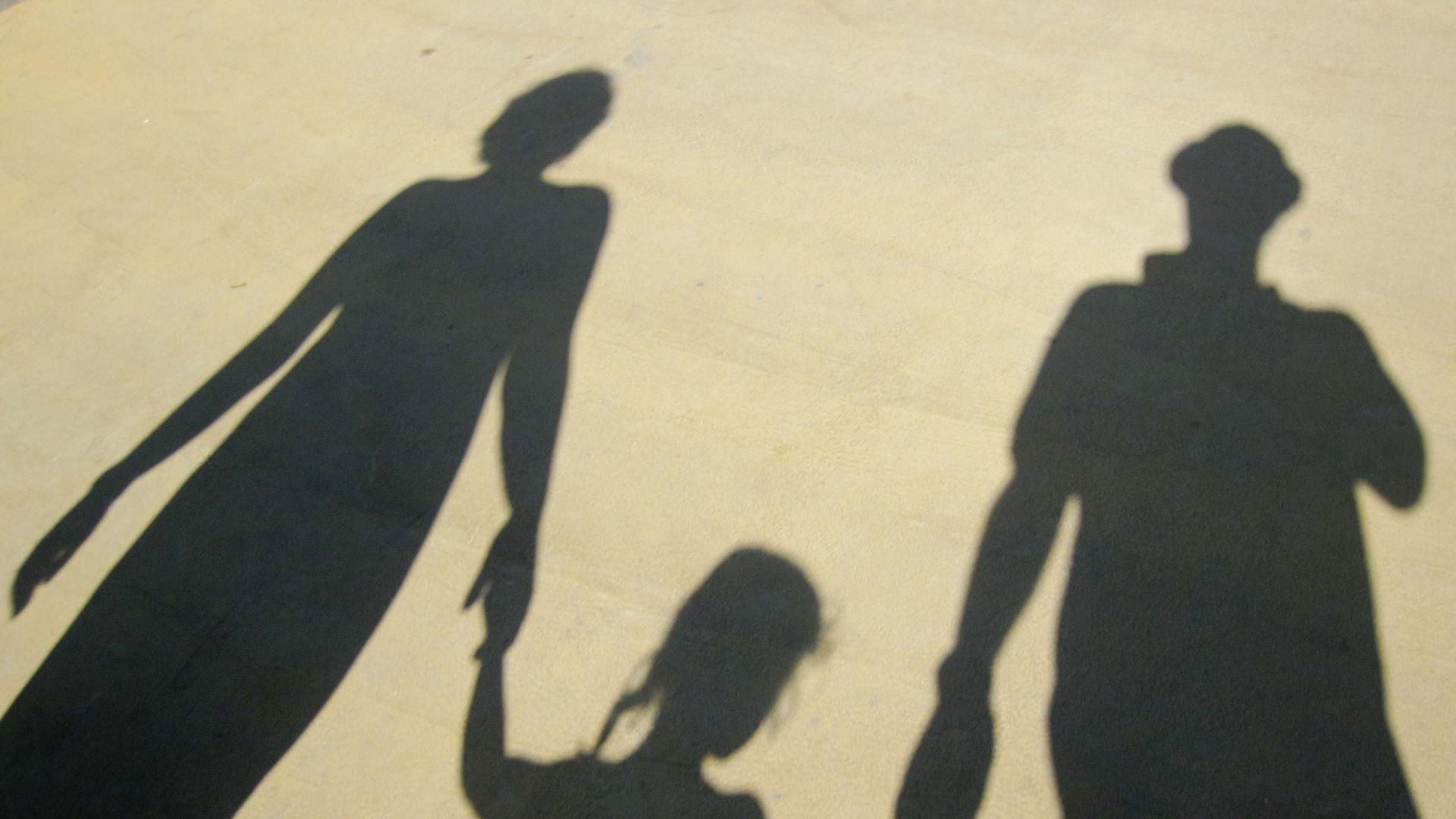 Der Schatten einer Familie, die sich an der Hand hält. Der Schatten einer Familie, die sich an der Hand hält.