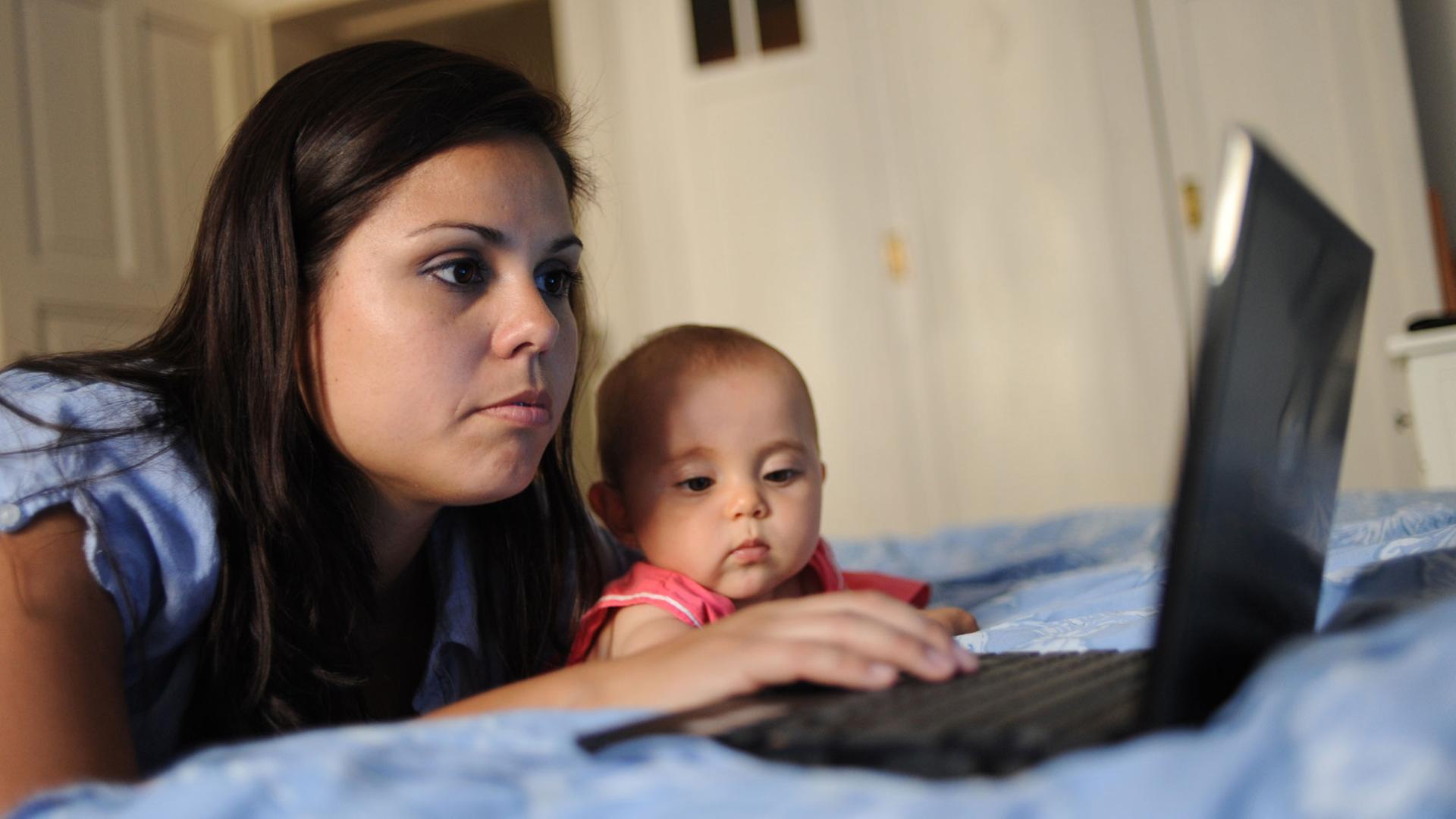 Eine Frau liegt am 10.6.2010 in ihrer Wohnung auf dem Bett und schaut auf einen Computerbildschirm, während ihre acht Monate alte Tochter daneben liegt und zuschaut.