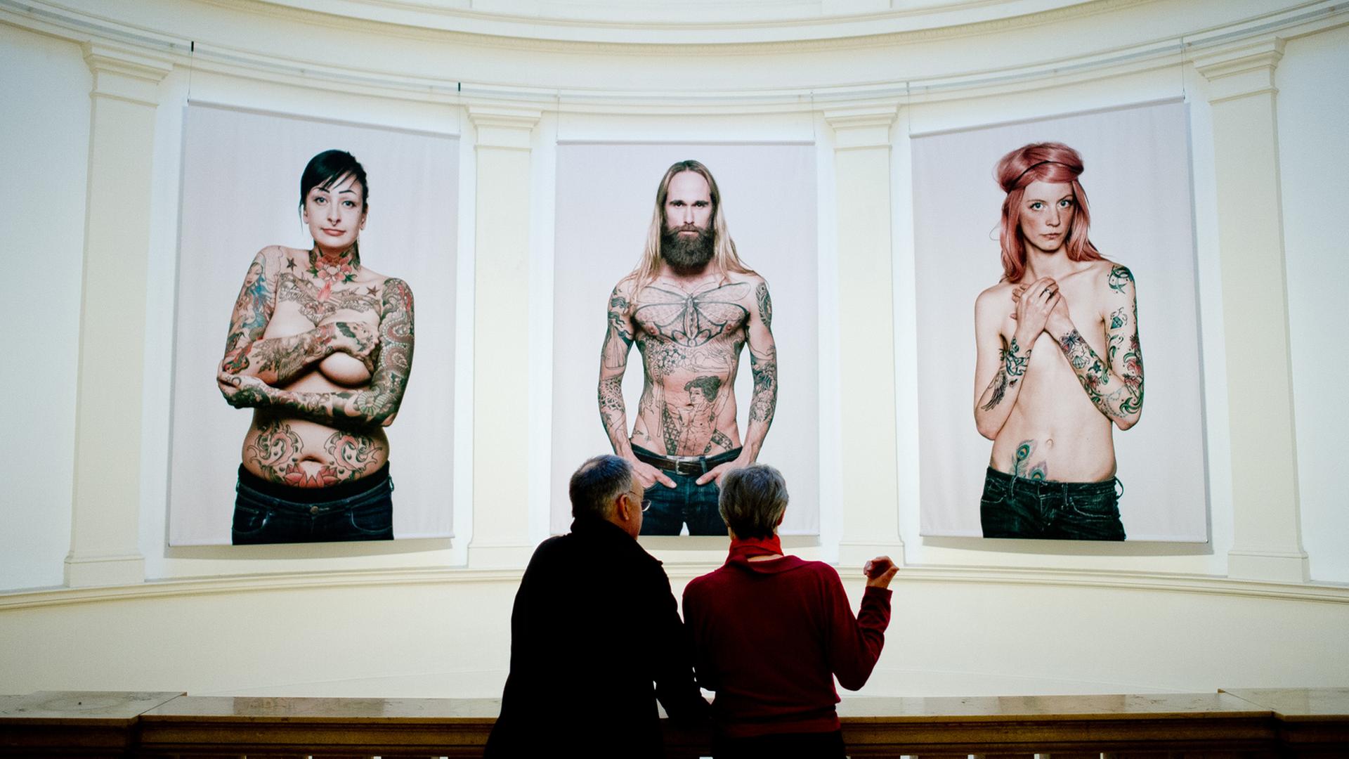 Ein Mann und eine Frau schauen sich in Hamburg im Museum für Kunst und Gewerbe (MKG) in der Ausstellung "Tattoo" Bilder von Tätowierten vom Fotografen Ralf Mitsch an. Ein Mann und eine Frau schauen sich in Hamburg im Museum für Kunst und Gewerbe (MKG) in der Ausstellung "Tattoo" Bilder von Tätowierten vom Fotografen Ralf Mitsch an.