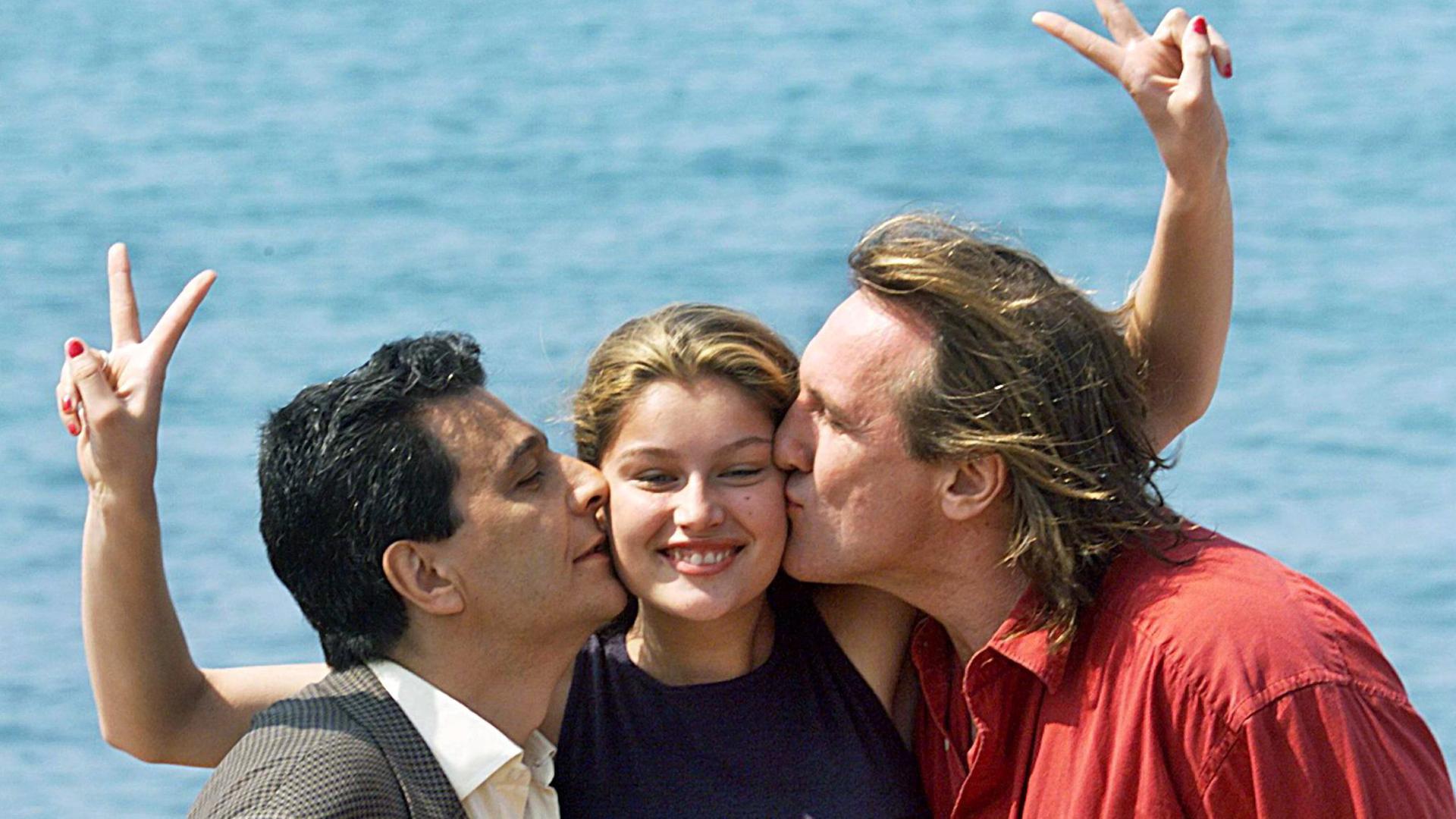 Die Schauspieler Christian Clavier und Gerard Depardieu küssen Model und Schauspielerin Laetitia Casta in Cannes, Archivfoto von 1998 Die Schauspieler Christian Clavier und Gerard Depardieu küssen Model und Schauspielerin Laetitia Casta in Cannes, Archivfoto von 1998