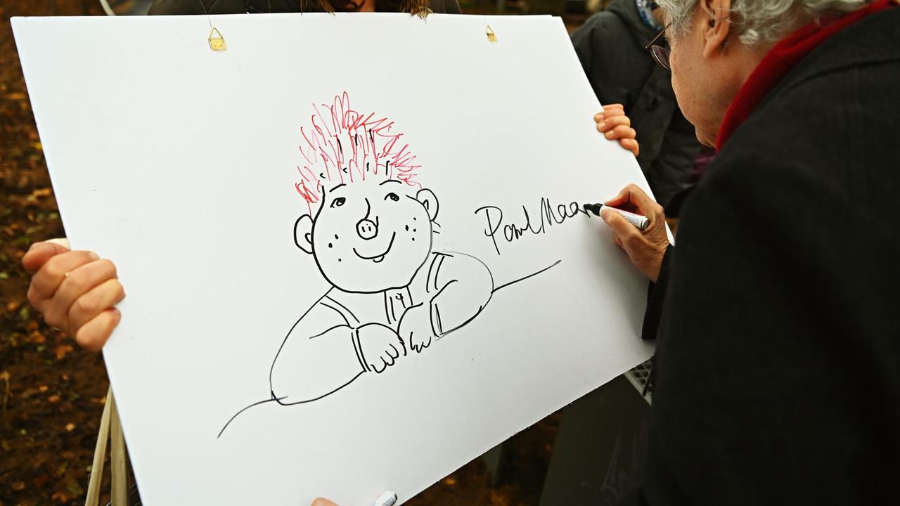 28.11.2019, Bayern, Bamberg: Die Kinderpflegerin Angela Göppner hält ein Plakat in den Händen, auf das der Kinderbuchautor Paul Maar ein Sams zeichnet. Die Installation einer Sams-Ampel wurde zusammen mit dem Kinderbuchautor Maar eingeweiht. 28.11.2019, Bayern, Bamberg: Die Kinderpflegerin Angela Göppner hält ein Plakat in den Händen, auf das der Kinderbuchautor Paul Maar ein Sams zeichnet. Die Installation einer Sams-Ampel wurde zusammen mit dem Kinderbuchautor Maar eingeweiht.