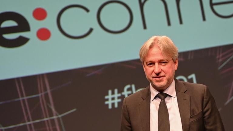 Juergen Boos, Direktor der Frankfurter Buchmesse, steht nach der Eröffnungspressekonferenz der Buchmesse vor einer Projektion des Buchmesse-Titels "Re:connect". Juergen Boos, Direktor der Frankfurter Buchmesse, steht nach der Eröffnungspressekonferenz der Buchmesse vor einer Projektion des Buchmesse-Titels "Re:connect".