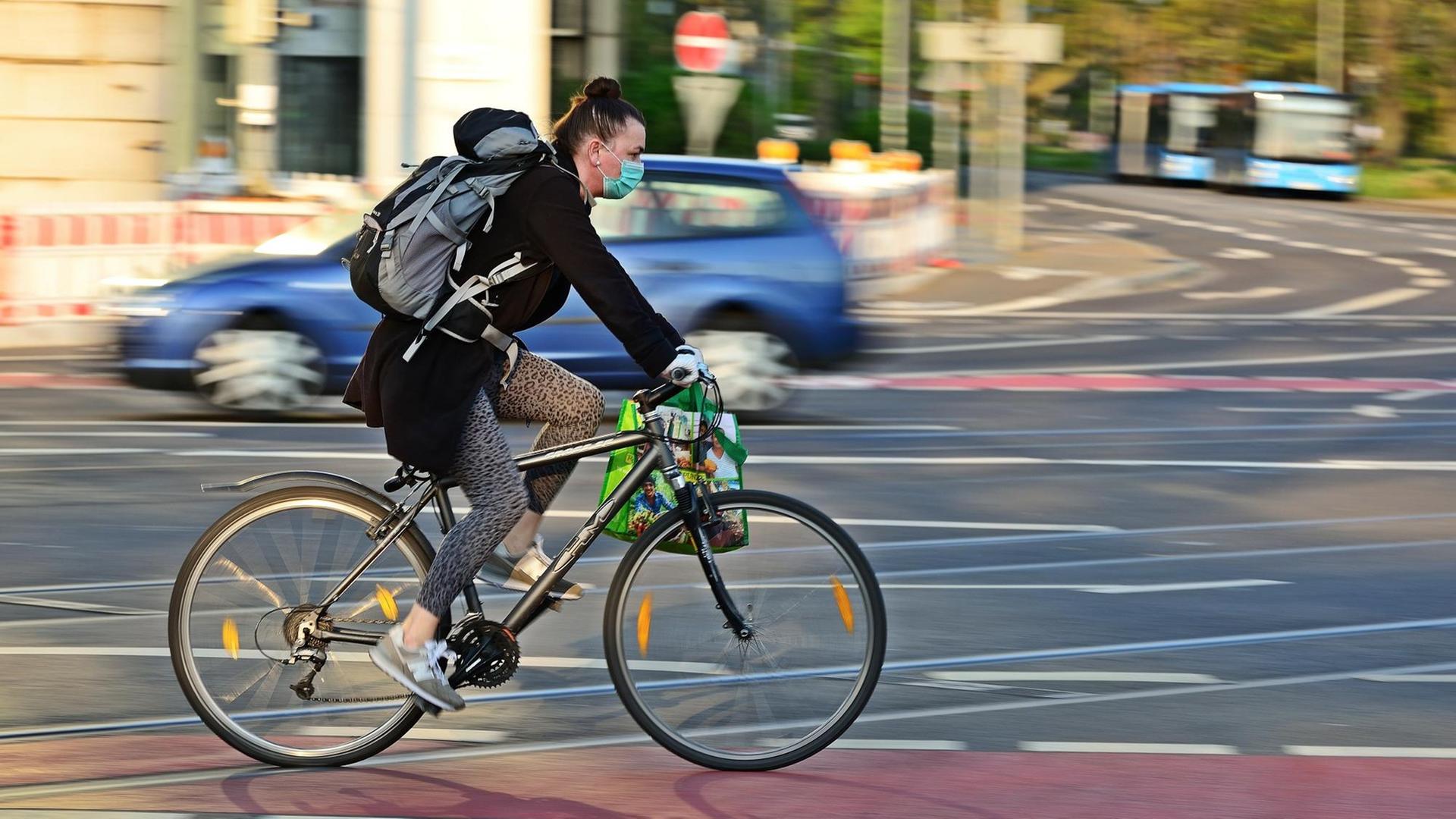 Radverkehr zu Zeiten der Corona-Pandemie. Eine Radfahrerin schützt sich mit einem Mundschutz vor einer Ansteckung mir dem Virus Radverkehr zu Zeiten der Corona-Pandemie. Eine Radfahrerin schützt sich mit einem Mundschutz vor einer Ansteckung mir dem Virus