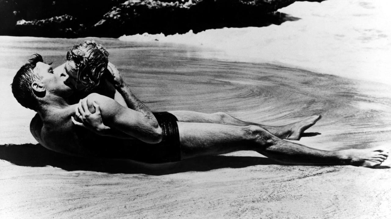 Ein Film-Still zeigt die Schauspielerin Deborah Kerr und Filmpartner Burt Lancaster bei einem Kuss am Strand von Hawaii von einer Welle umspült
Ein Film-Still zeigt die Schauspielerin Deborah Kerr und Filmpartner Burt Lancaster bei einem Kuss am Strand von Hawaii von einer Welle umspült