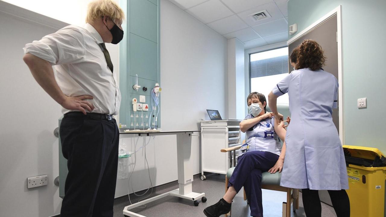 Der britische Premierminister Boris Johnson schaut zu, wie die Assistenzschwester Susan Cole mit dem Oxford-AstraZeneca Covid-19-Impfstoff am 4.1.2021 im Chase Farm Hospital in Nord-London, Teil des Royal Free London NHS Foundation Trust, geimpft wird.