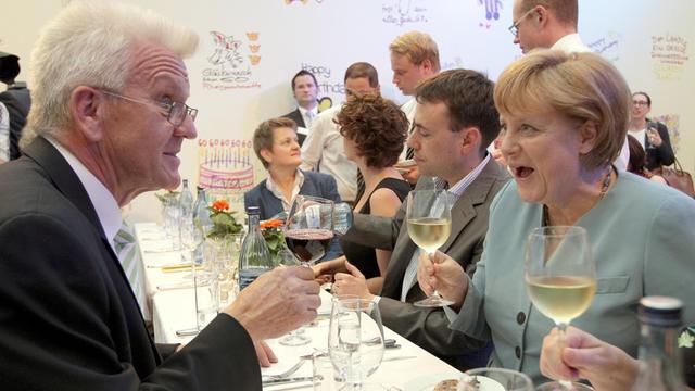 Der Ministerpräsident von Baden-Württemberg, Winfried Kretschmann (Grüne) und Bundeskanzlerin Angela Merkel (CDU) stoßen am Donnerstag (05.07.2012) auf der Stallwächter-Party, das Sommerfest des Landes Baden-Württemberg in Berlin, mit Wein an.