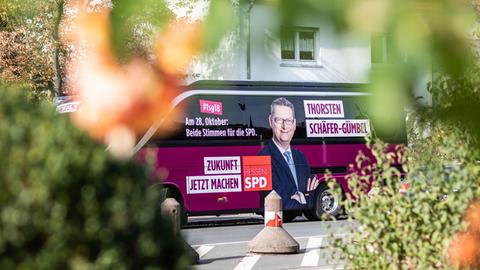 Im Vordergrund verschwommene Büsche, im Hintergrund der Wahlkampfbus des Spitzenkandidaten der Hessen-SPD Thorsten Schäfer-Gümbel.