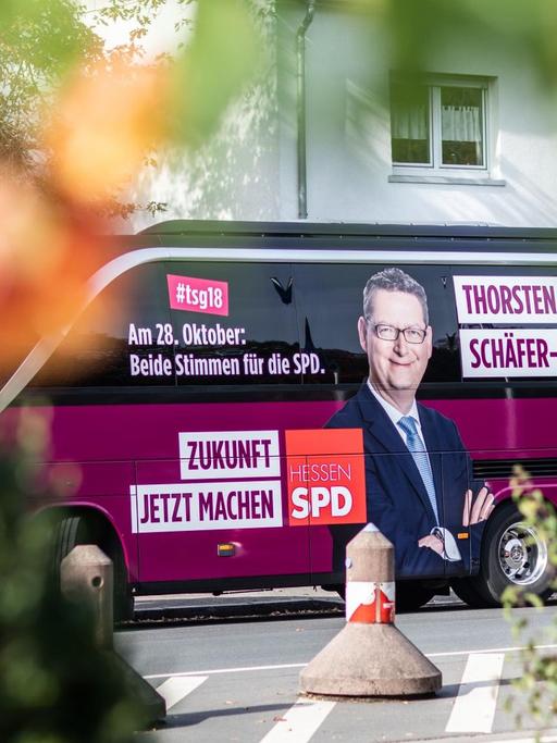 Im Vordergrund verschwommene Büsche, im Hintergrund der Wahlkampfbus des Spitzenkandidaten der Hessen-SPD Thorsten Schäfer-Gümbel.