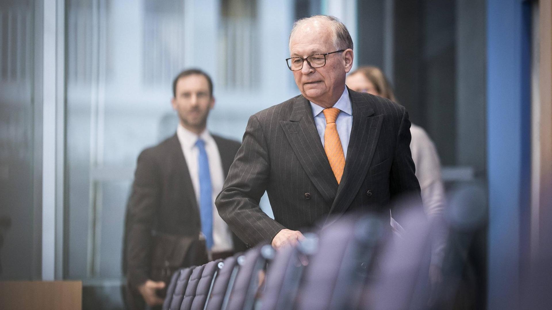 Wolfgang Ischinger im Rahmen einer Pressekonferenz in Berlin. Er geht an einer Stuhlreihe vorbei. Ernster Gesichtsausdruck, Nadelstreifenanzug, hellblaues Hemd und orangene Krawatte. Wolfgang Ischinger im Rahmen einer Pressekonferenz in Berlin. Er geht an einer Stuhlreihe vorbei. Ernster Gesichtsausdruck, Nadelstreifenanzug, hellblaues Hemd und orangene Krawatte.