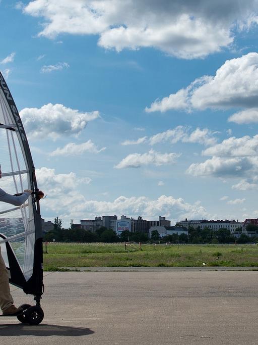 Auf dem alten Flughafen Tempelhof ist auch viel Platz für Sportler. Hier sehen wir einen Wind-Surfer auf einem Brett mit Rollen und Segel.