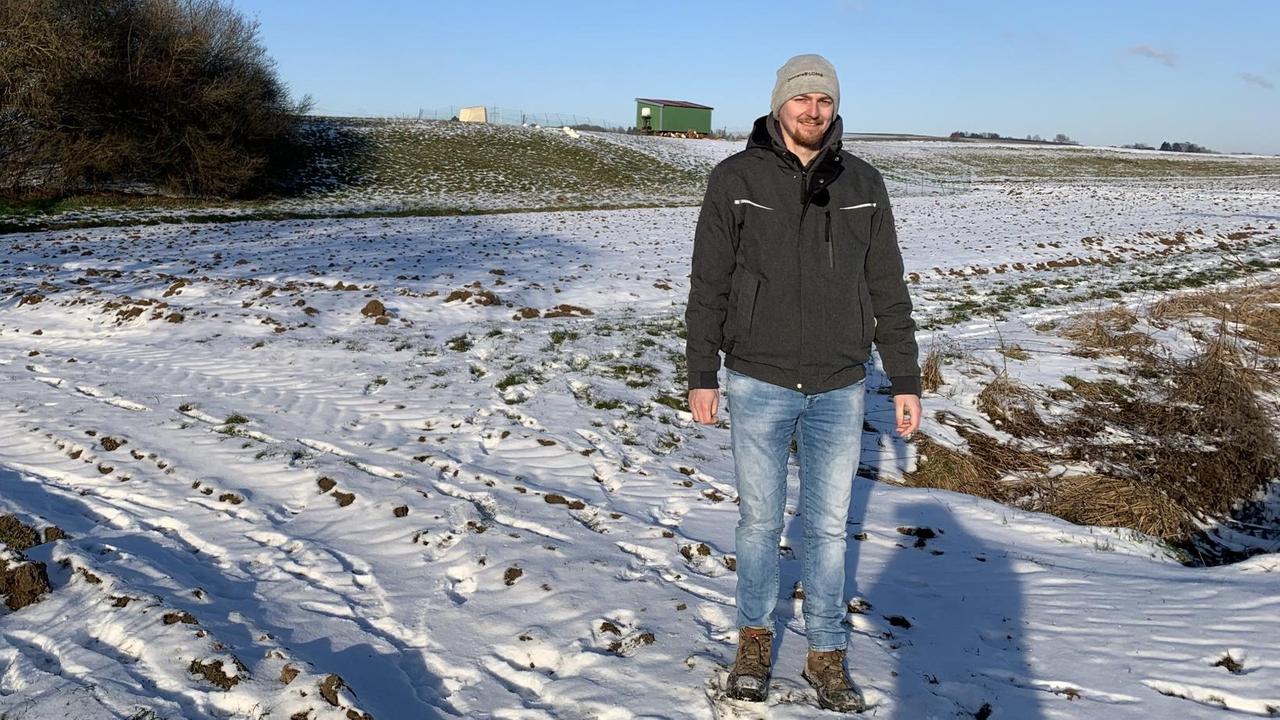 Michael Kreß ist Ackerbauer in einem Familienbetrieb im Norden von Baden-Württemberg. Hier steht er neben seinem schneebedecktem Feld.
