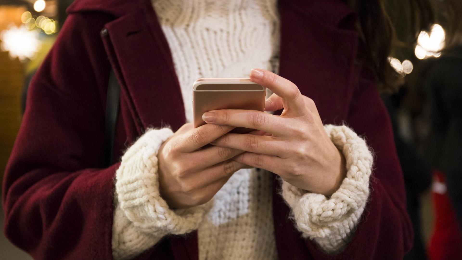 Eine Frau hält ein Smartphone in den Händen Eine Frau hält ein Smartphone in den Händen