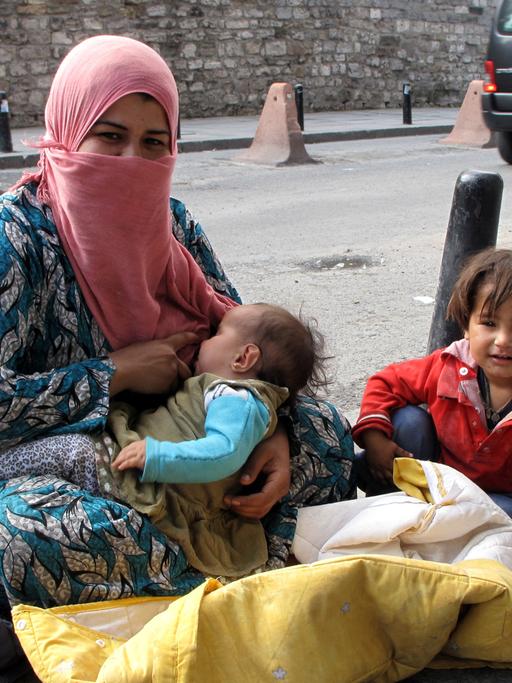 Die Syrerin Fatima mit ihren Kindern auf dem staubigen Bürgersteig einer Straße in Istanbul und bettelt, aufgenommen 2014.