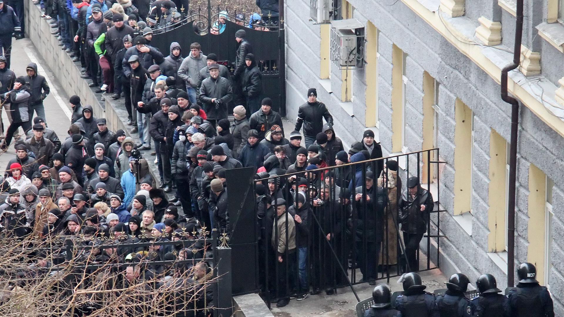 Prorussische Demonstranten, die ein Gebäude der Regionalverwaltung im ukrainischen Donezk erstürmt haben, stehen Polizisten gegenüber.