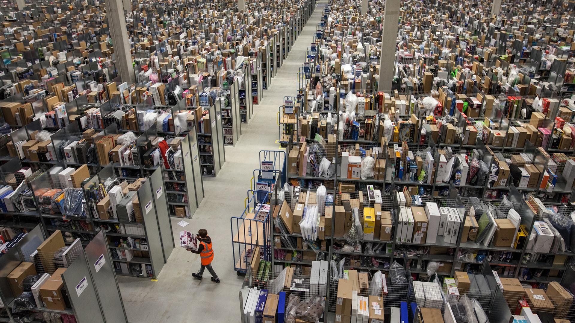 Eine Mitarbeiterin von Amazon läuft in einer der Lagerhallen des Amazon Logistikzentrums in Pforzheim an tausenden unverpackten Kartons vorbe. Eine Mitarbeiterin von Amazon läuft in einer der Lagerhallen des Amazon Logistikzentrums in Pforzheim an tausenden unverpackten Kartons vorbe.