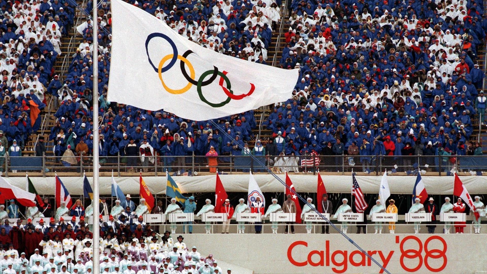 Die Fahne mit den Olympischen Ringen weht im McMahon-Stadion - aufgenommen während der Eröffnungsfeier der Olympischen Winterspiele 1988 in Calgary, Kanada. Die Fahne mit den Olympischen Ringen weht im McMahon-Stadion - aufgenommen während der Eröffnungsfeier der Olympischen Winterspiele 1988 in Calgary, Kanada.