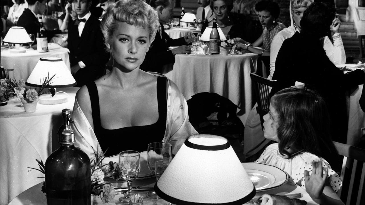 Die Schauspielerin Martine Carole sitzt in einem Restaurant. Ausschnitt aus dem Film "Der Skandal".