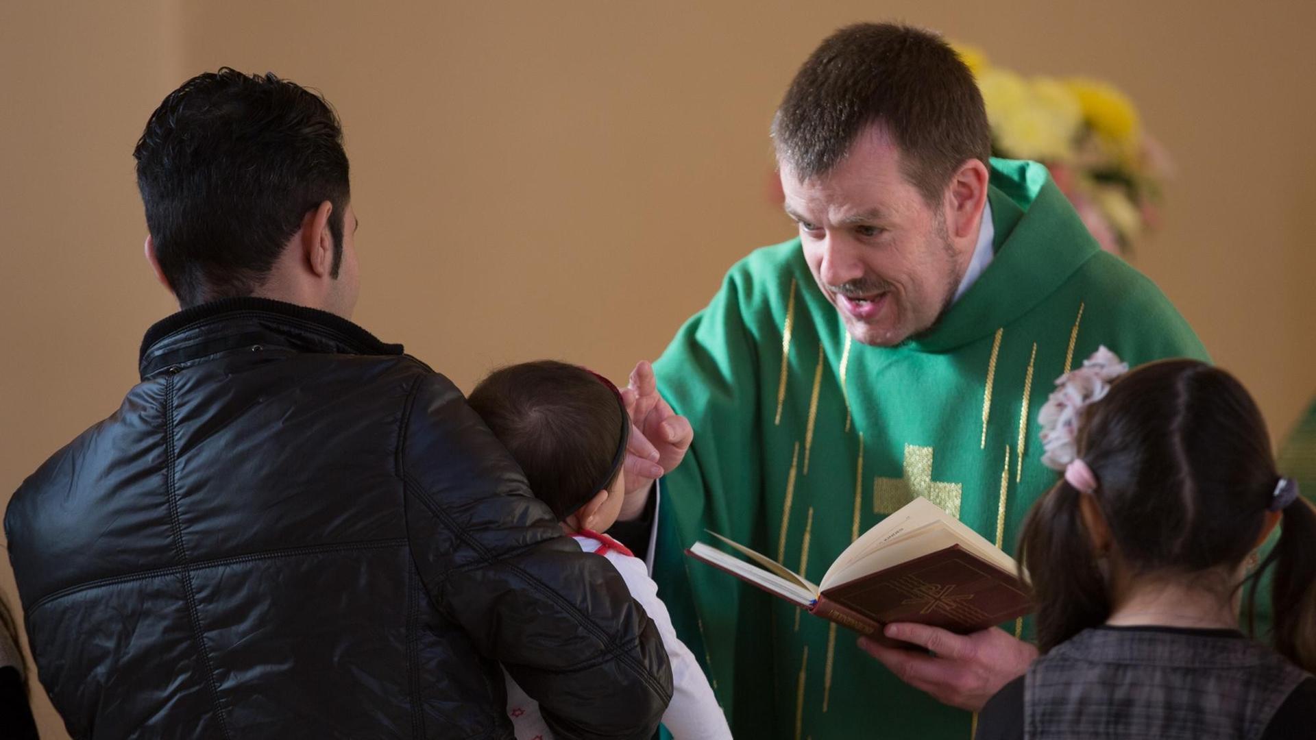 Pastor Gottfried Martens segnet das kleine Mädchen Meliza auf dem Arm ihres Vaters vor ihrer Taufe. Pastor Gottfried Martens segnet das kleine Mädchen Meliza auf dem Arm ihres Vaters vor ihrer Taufe.