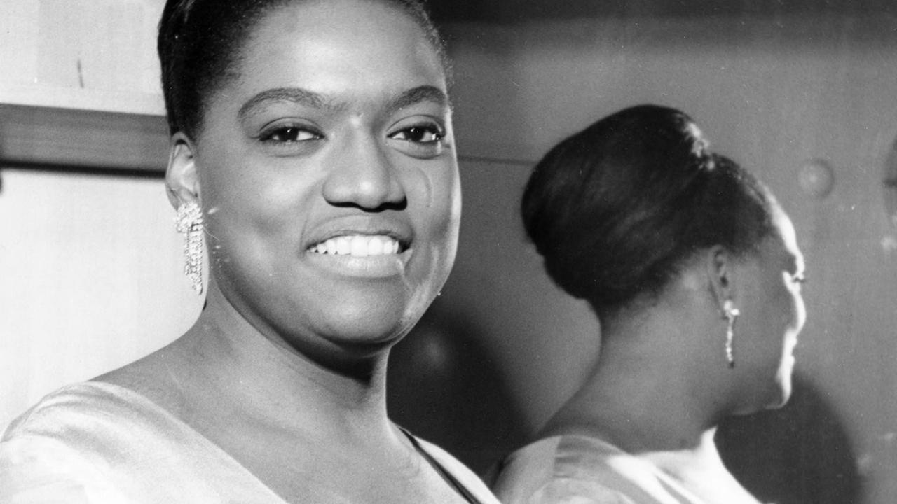 Eine Archivaufnahme zeigt Jessye Norman im RIAS 1969. Sie steht an einen Spiegel gelehnt, so dass sich ihr Hinterkopf darin spiegelt. Eine Archivaufnahme zeigt Jessye Norman im RIAS 1969. Sie steht an einen Spiegel gelehnt, so dass sich ihr Hinterkopf darin spiegelt.
