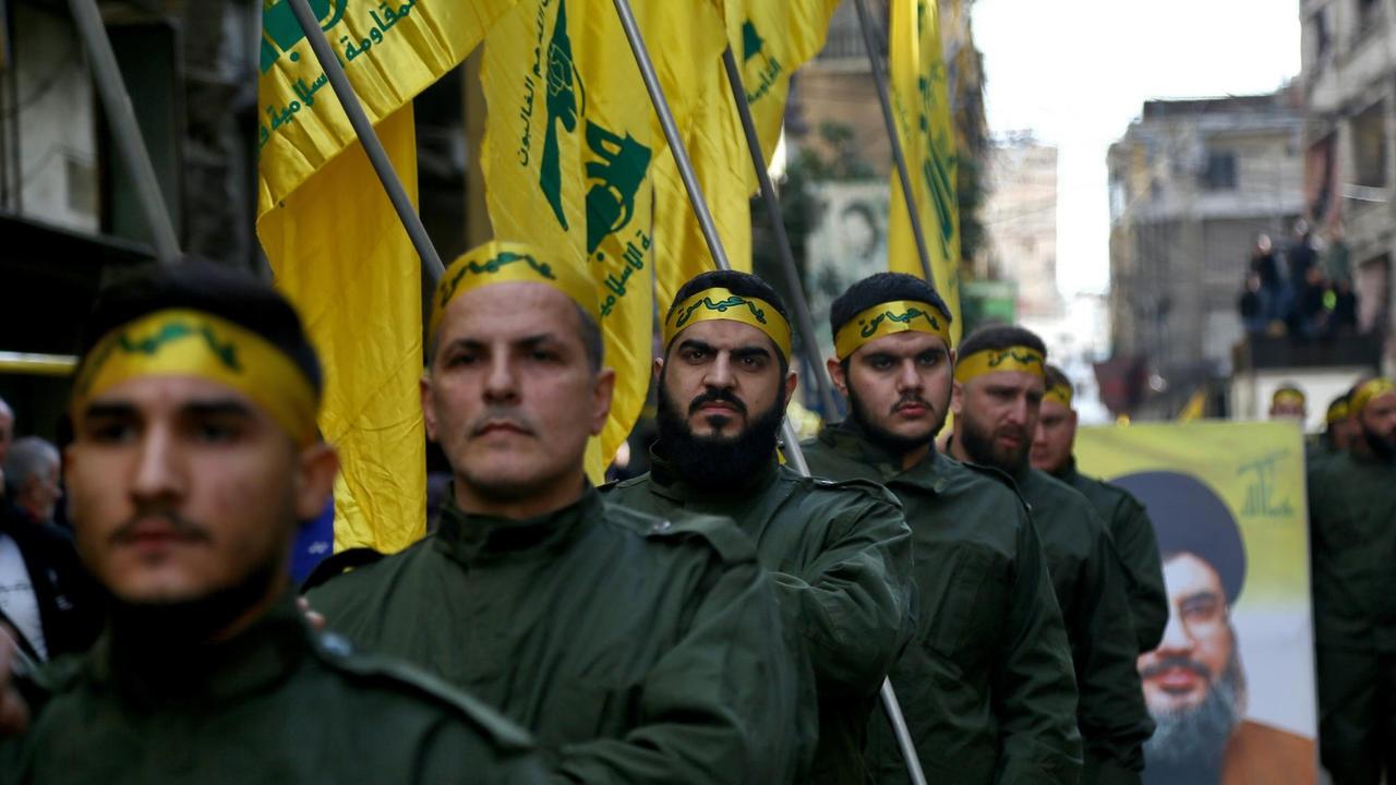 Pro-iranische Hisbollah-Kämpfer halten während des Trauerzuges von fünf ihrer Kollegen, die bei Zusammenstößen mit der türkischen Armee in der syrischen Provinz Idlib getötet wurden, Fahnen in der Hand. Pro-iranische Hisbollah-Kämpfer halten während des Trauerzuges von fünf ihrer Kollegen, die bei Zusammenstößen mit der türkischen Armee in der syrischen Provinz Idlib getötet wurden, Fahnen in der Hand.