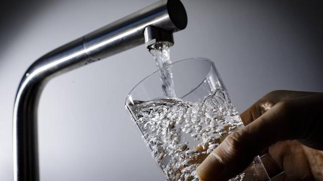 Symbolfoto: Wasser fliesst aus einem Wasserhahn in ein Glas.