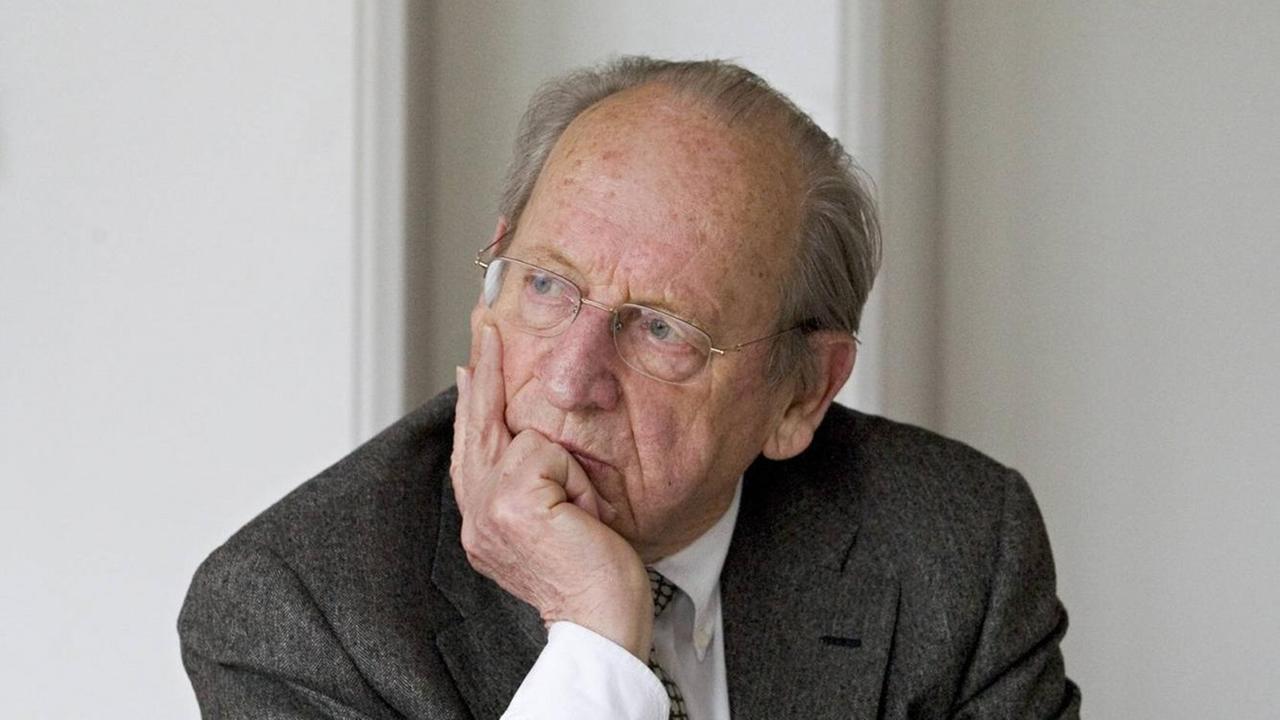 Porträt von Günther Rühle, der an einem Tisch sitzt und das Kinn auf seine Hand stützt. Porträt von Günther Rühle, der an einem Tisch sitzt und das Kinn auf seine Hand stützt.