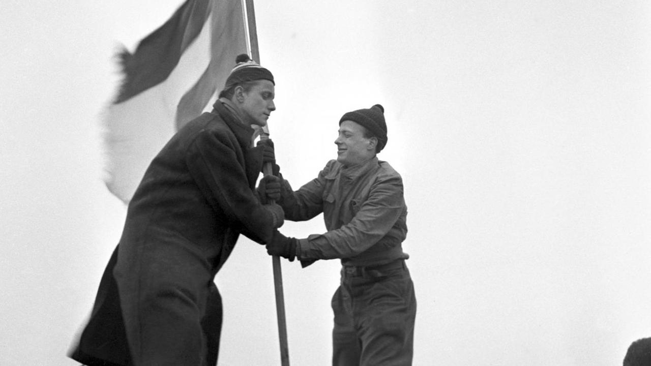 Ein Schwarz-Weiß-Bild zeigt die beiden Studenten Georg von Hatzfeld (l) und Rene Leudesdorff 1951 beim Hissen der Europafahne auf einem F-else der Nordseeinsel Helgoland