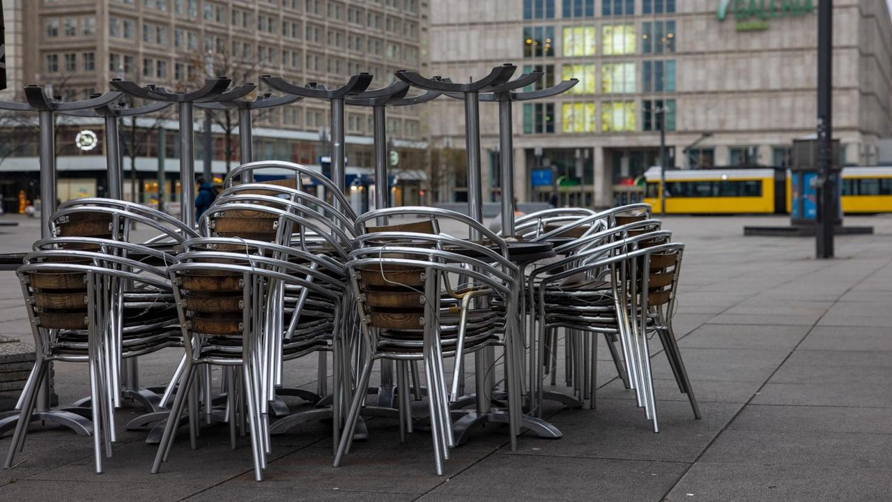 Auf dem Berliner Alexanderplatz sind Tische und Stühle eines Restaurants gestapelt und zusammengestellt. Auf dem Berliner Alexanderplatz sind Tische und Stühle eines Restaurants gestapelt und zusammengestellt.