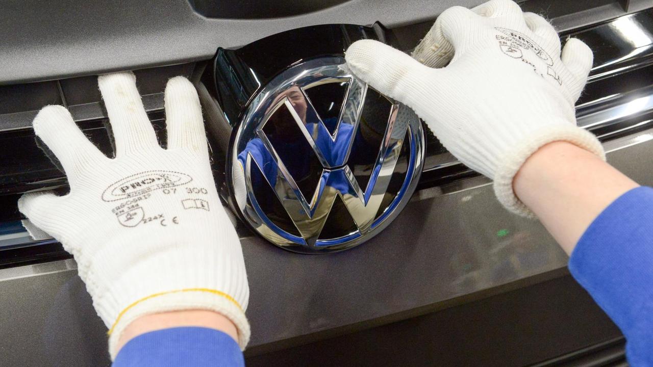 Man sieht zwei Hände in weißen Stoffhandschuhen, die das Logo anbringen. Man sieht zwei Hände in weißen Stoffhandschuhen, die das Logo anbringen.