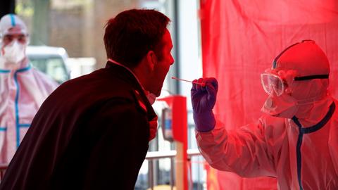 Einem Mitarbeiter der Berufsfeuerwehr Köln wird im dritten Infektionsschutzzentrum der Stadt Köln mit einem Stäbchen ein Abstrich für einen Test auf den Coronavirus entnommen.