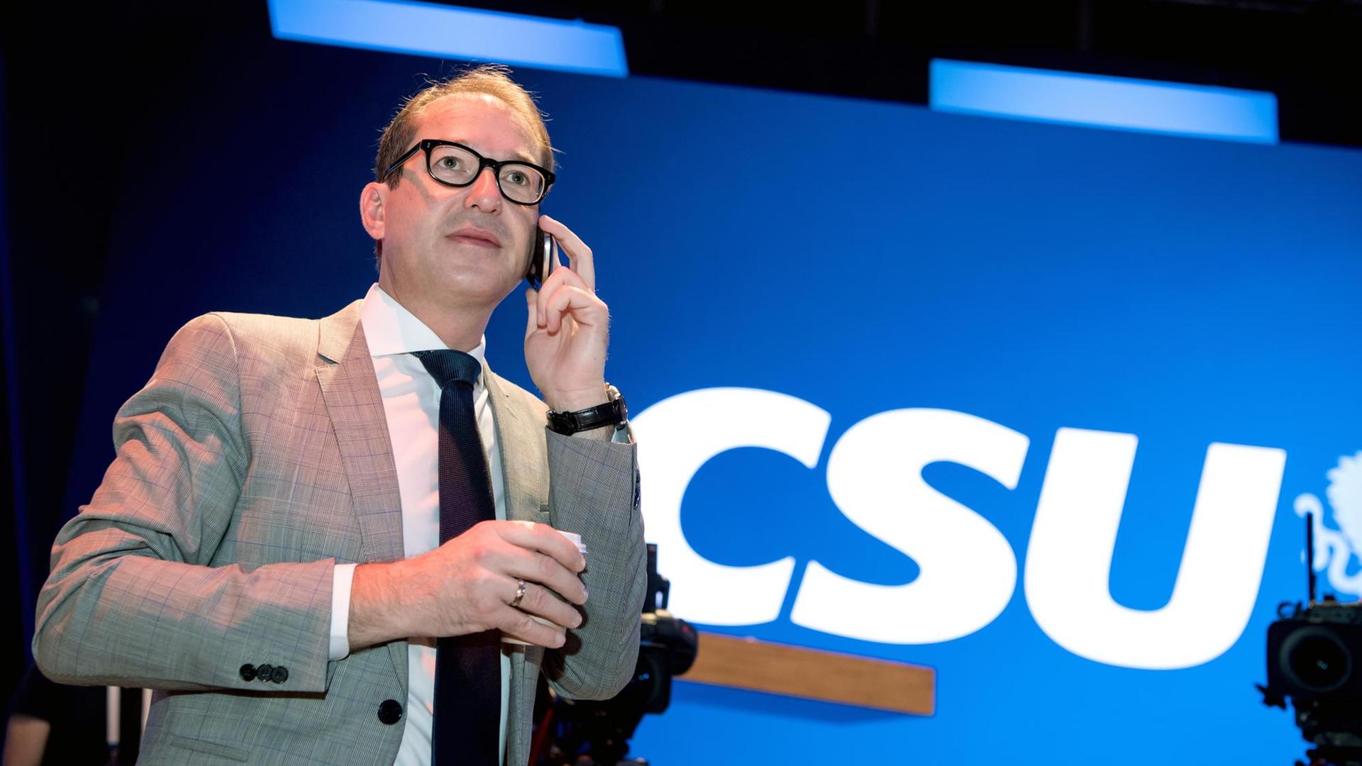 Alexander Dobrindt telefoniert, im Hintergrund der Schriftzug CSU auf blauem Hintergrund. Alexander Dobrindt telefoniert, im Hintergrund der Schriftzug CSU auf blauem Hintergrund.