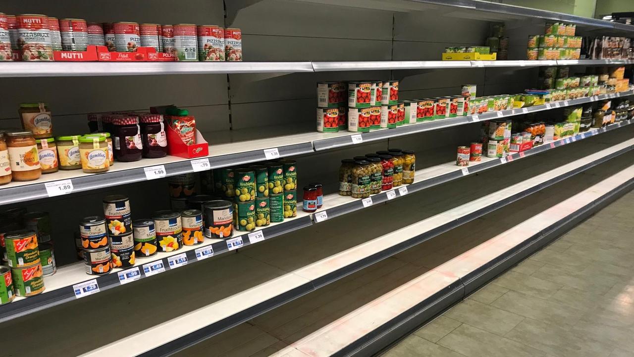 Ein Supermarktregal, das nur noch zur Hälfte mit Konserven gefüllt ist. Ein Supermarktregal, das nur noch zur Hälfte mit Konserven gefüllt ist.