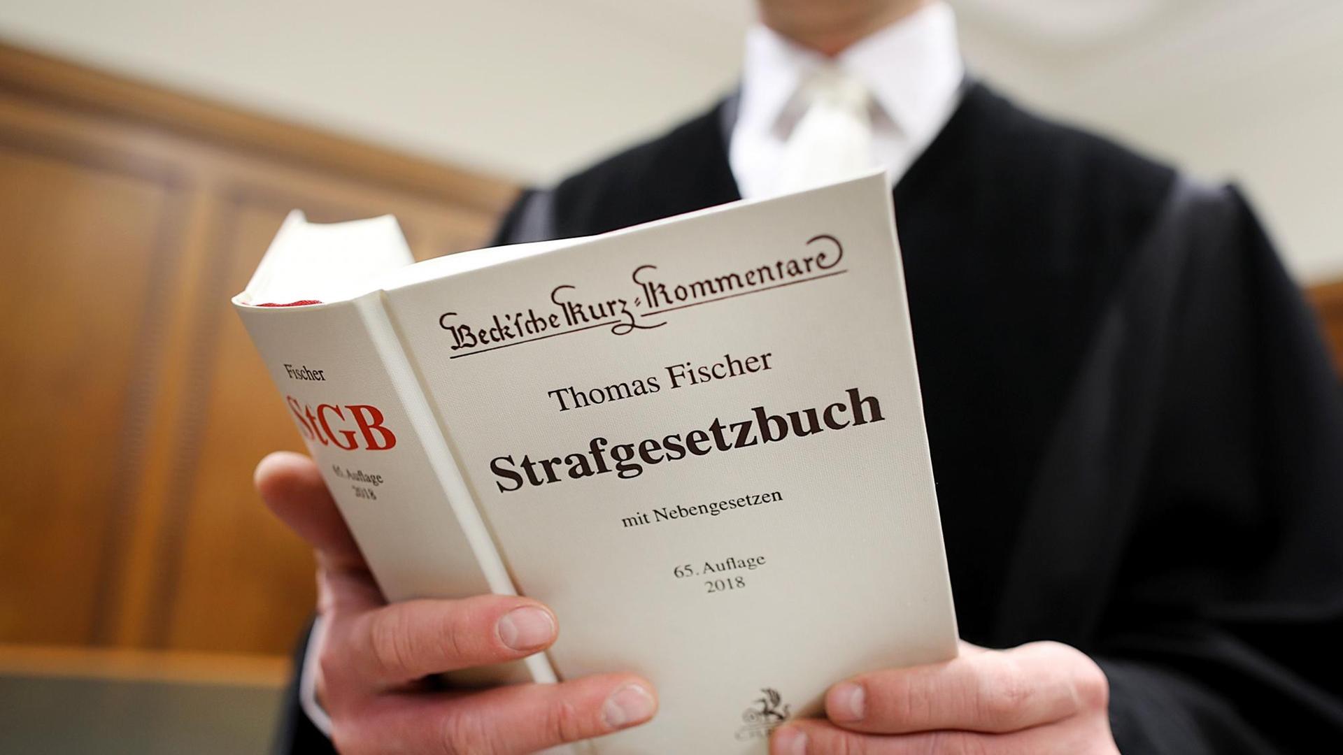Ein Richter hält das Straf-Gesetz-Buch in der Hand. Ein Richter hält das Straf-Gesetz-Buch in der Hand.
