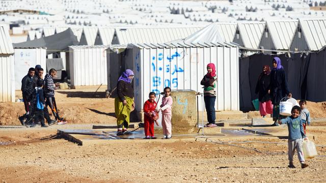 Syrer stehen am 08.12.2015 im Lager für syrische Flüchtlinge des Flüchtlingswerks der Vereinten Nationen (UNHCR) in Azraq (Jordanien) an einer Wasserstelle. (UNHCR) geführt und liegt rund 100 Kilometer östlich der Hauptstadt Amman in der Wüste. Derzeit leben dort nach UN-Angaben rund 28 300 Menschen.
